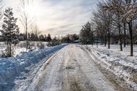 an empty snowy street is shown on a sunny day the road is empty and covered in snow