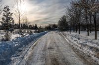 an empty snowy street is shown on a sunny day the road is empty and covered in snow