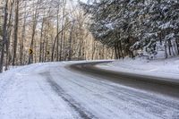 a curved road is bordered by trees on a snow covered mountain side and the road is very icy and snowy