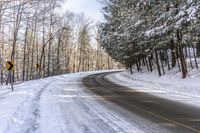 a curved road is bordered by trees on a snow covered mountain side and the road is very icy and snowy