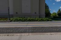 a bricked median along a street in front of an empty building and two trees