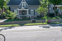 a bicycle is parked along a curb in front of a home, with the bicycle leaning on the curb