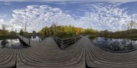 a fish eye lens looking down into the woods at a small dock with a boat in the water