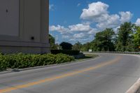 an empty asphalt road with trees in the distance, with no cars at the end