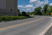 an empty asphalt road with trees in the distance, with no cars at the end