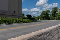 an empty asphalt road with trees in the distance, with no cars at the end