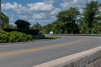 an empty asphalt road with trees in the distance, with no cars at the end