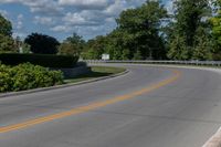 an empty asphalt road with trees in the distance, with no cars at the end