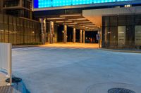 the view from the parking meter of a large building at night time, showing the entrance to a hotel