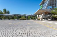 an empty parking lot with buildings in the background and blue skies above it in a sunny day