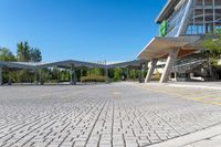 an empty parking lot with buildings in the background and blue skies above it in a sunny day