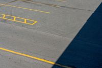 an empty parking lot with some yellow markings on it and black ground and white wall