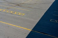 an empty parking lot with some yellow markings on it and black ground and white wall