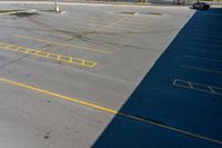 an empty parking lot with some yellow markings on it and black ground and white wall