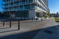 an empty road with concrete poles on both sides of it and buildings in the background