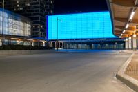 a large building with a big blue screen in the front of it at night time