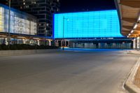 a large building with a big blue screen in the front of it at night time