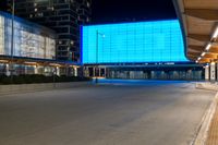 a large building with a big blue screen in the front of it at night time