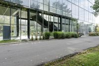 a big glass building with many trees in front of it that is part of a walkway