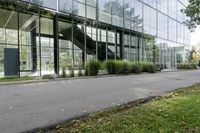 a big glass building with many trees in front of it that is part of a walkway