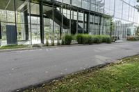 a big glass building with many trees in front of it that is part of a walkway