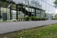 a big glass building with many trees in front of it that is part of a walkway