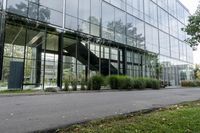 a big glass building with many trees in front of it that is part of a walkway