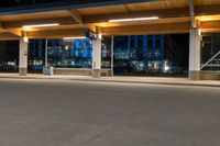 an empty parking lot filled with lots of lights at night time near a city street