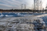 the road is full of snow and gravel on a cold day the sun shines brightly