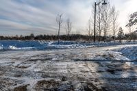 the road is full of snow and gravel on a cold day the sun shines brightly