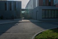 an empty sidewalk outside of a building, with sun shining down on it and grass in the foreground