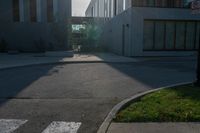 an empty sidewalk outside of a building, with sun shining down on it and grass in the foreground