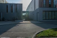 an empty sidewalk outside of a building, with sun shining down on it and grass in the foreground