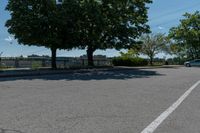 a black car driving down an empty street by some trees and bushes on either side