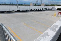 a parking lot in an industrial building with several yellow lines and white columns on it