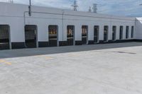 empty parking area with large industrial building in the background that has no cars in front of it