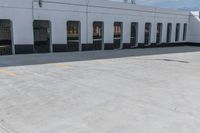 empty parking area with large industrial building in the background that has no cars in front of it