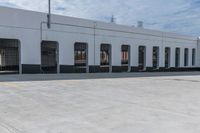 empty parking area with large industrial building in the background that has no cars in front of it