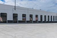 empty parking area with large industrial building in the background that has no cars in front of it