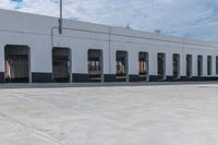 empty parking area with large industrial building in the background that has no cars in front of it