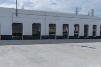 empty parking area with large industrial building in the background that has no cars in front of it
