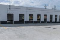 empty parking area with large industrial building in the background that has no cars in front of it