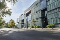 a building with a view of trees and shrubs in front of it as a pedestrian crosses the street