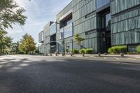 a building with a view of trees and shrubs in front of it as a pedestrian crosses the street