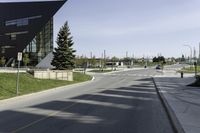 view down a wide empty road in an urban area with tall buildings and trees along both sides