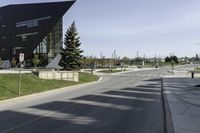 view down a wide empty road in an urban area with tall buildings and trees along both sides