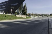 view down a wide empty road in an urban area with tall buildings and trees along both sides