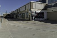 a building is in the middle of a cement parking lot, which has a large hole on the floor