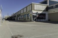 a building is in the middle of a cement parking lot, which has a large hole on the floor