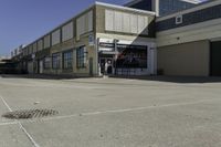 a building is in the middle of a cement parking lot, which has a large hole on the floor